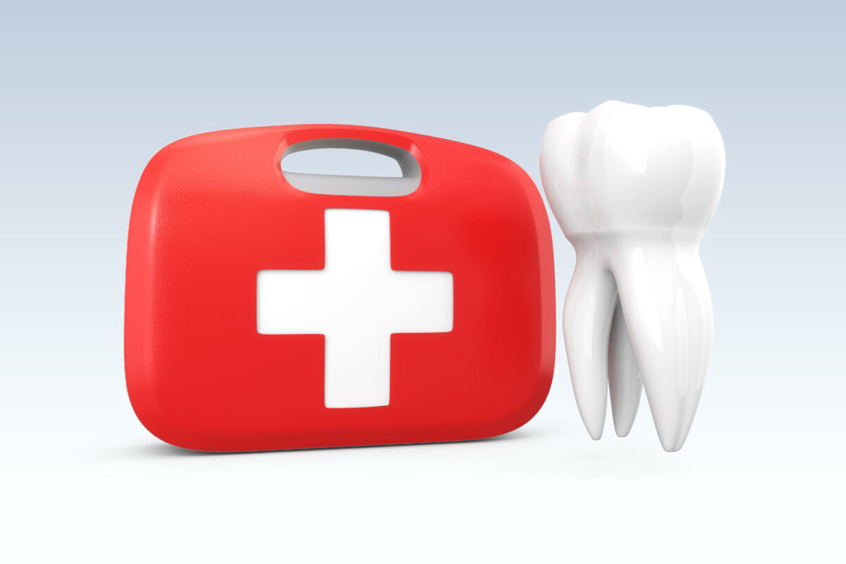 A white tooth floats next to a red and white first aid kit for a dental emergency