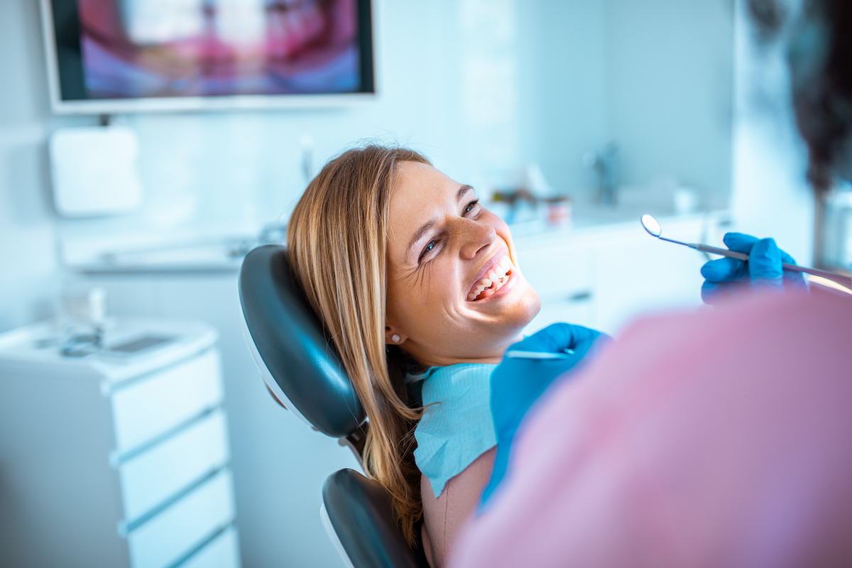 Blonde woman smiles while leaning back in a dental chair at her dentist in Pawtucket, RI