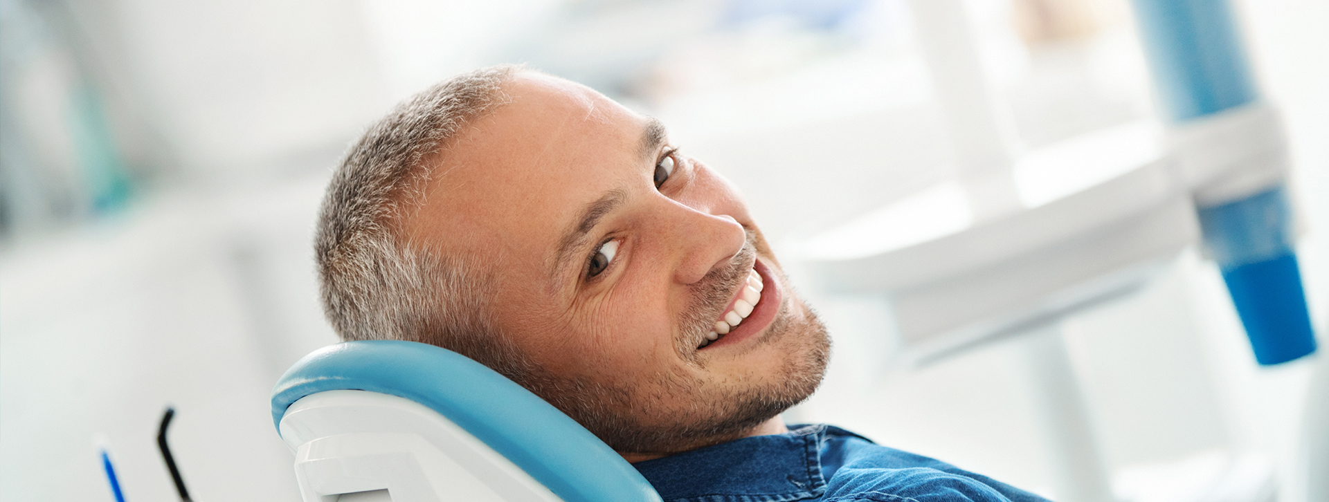 man sitting in dental chair and smiling over his shoulder